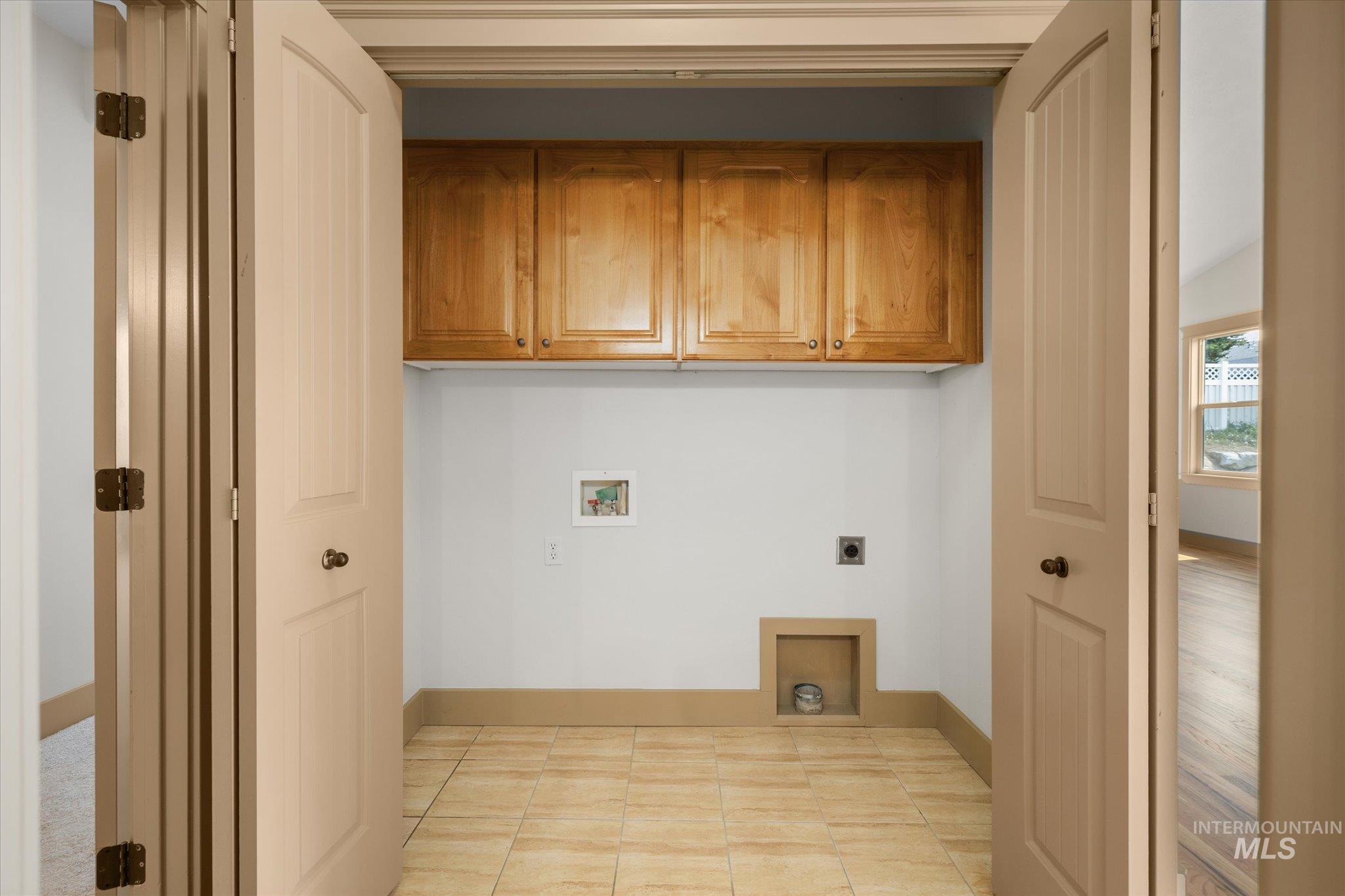Laundry room featuring cabinet space, electric dryer hookup, hookup for a washing machine, and light tile patterned floors