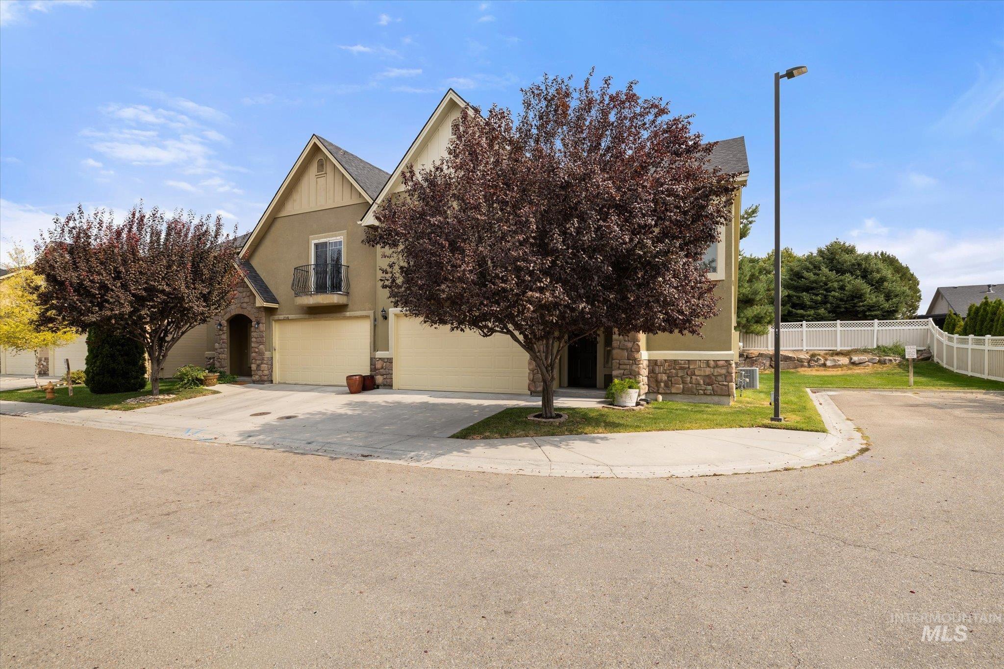 Obstructed view of property with stone siding, driveway, an attached garage, and stucco siding