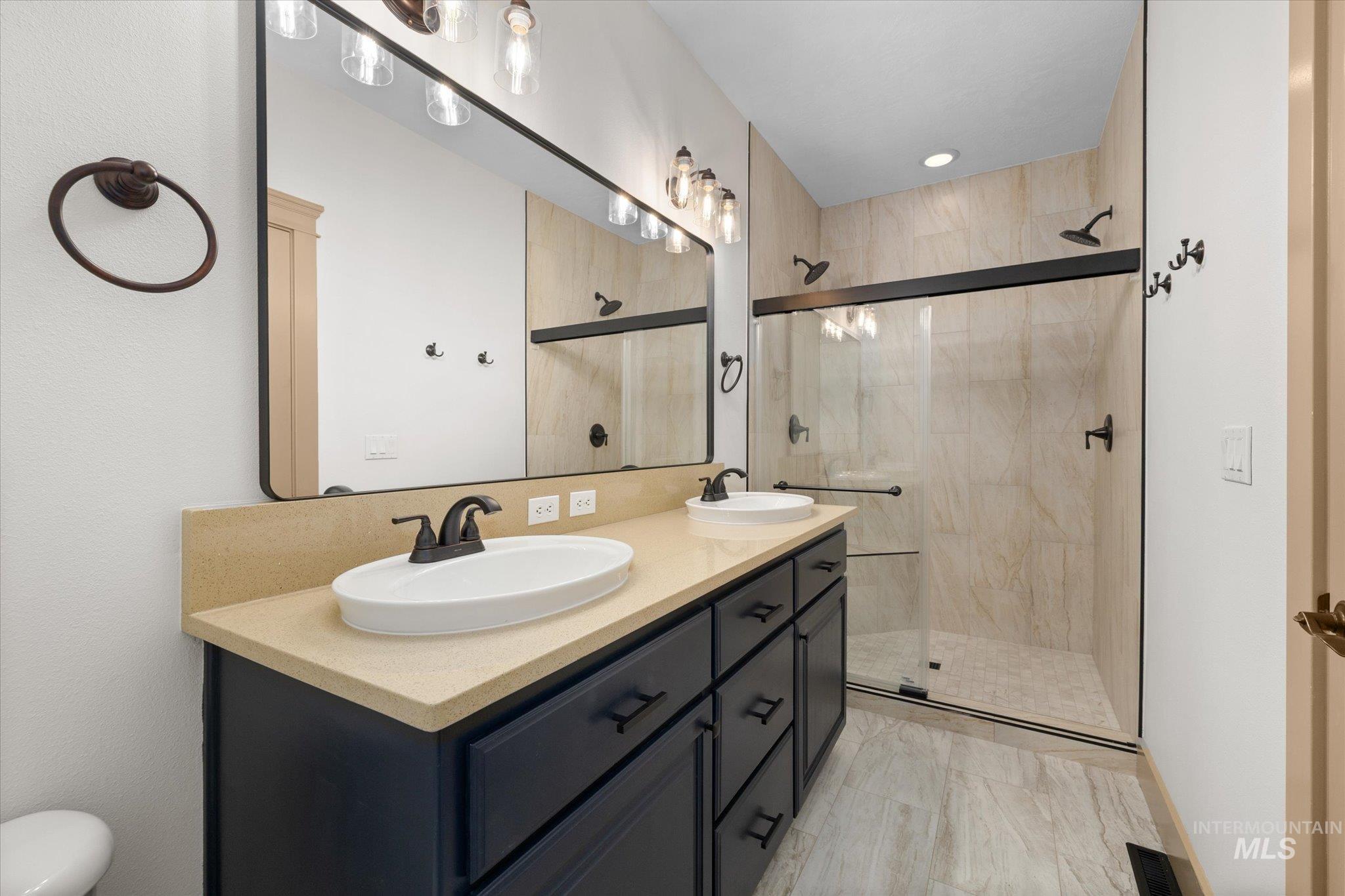 Primary Bathroom with a shower stall and double vanity
