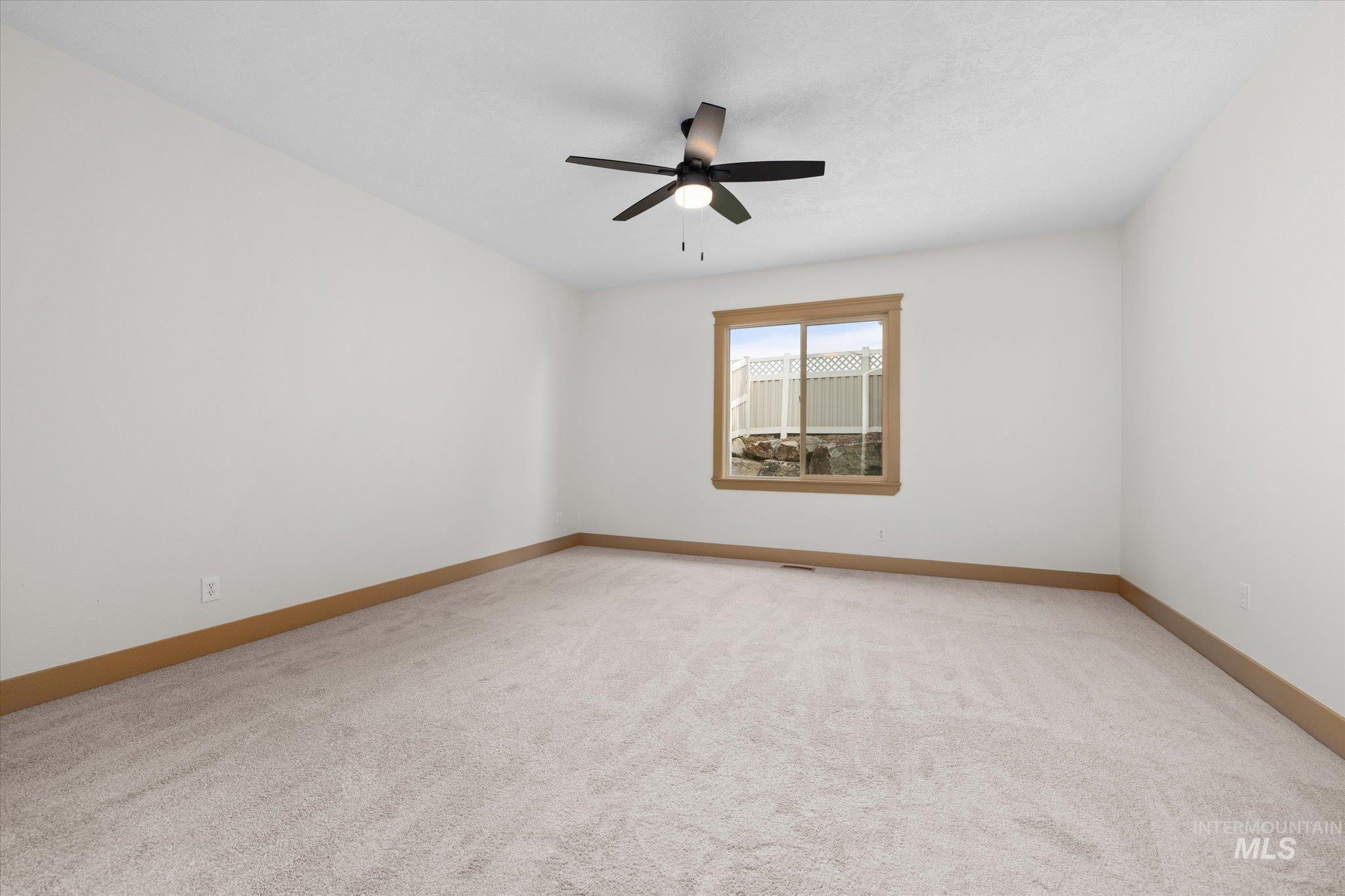 Empty room featuring light colored carpet and ceiling fan