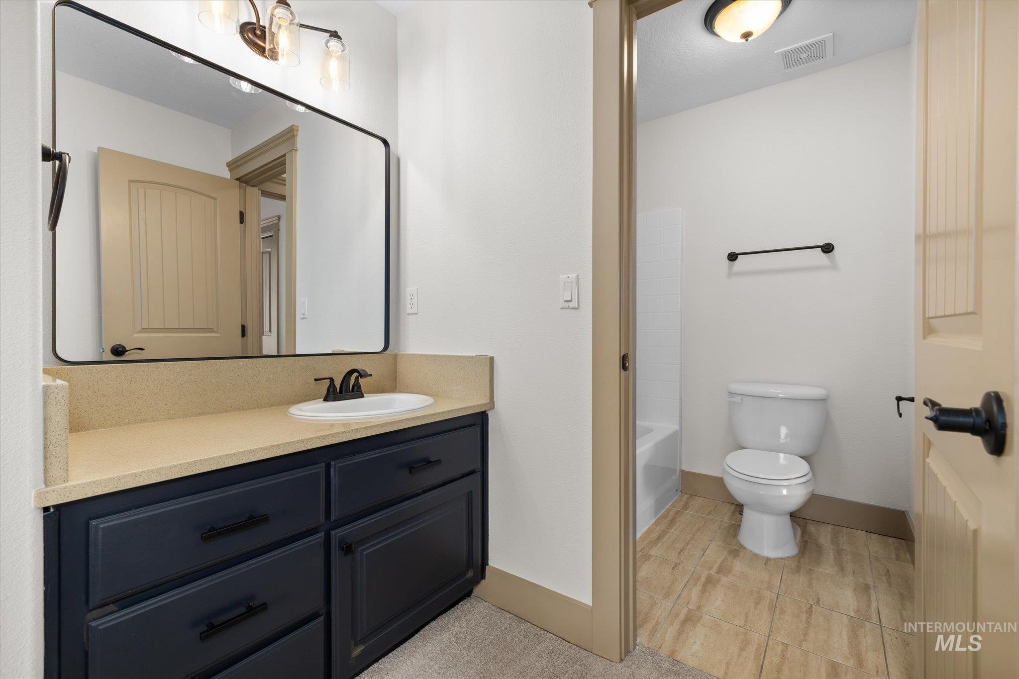 Full bath featuring vanity, light tile patterned flooring, and shower / bathtub combination
