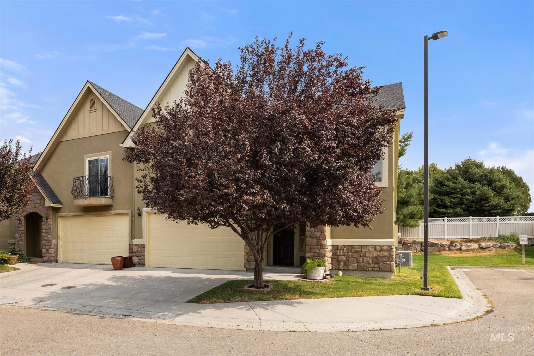 Obstructed view of property featuring stone siding, an attached garage, concrete driveway, and stucco siding