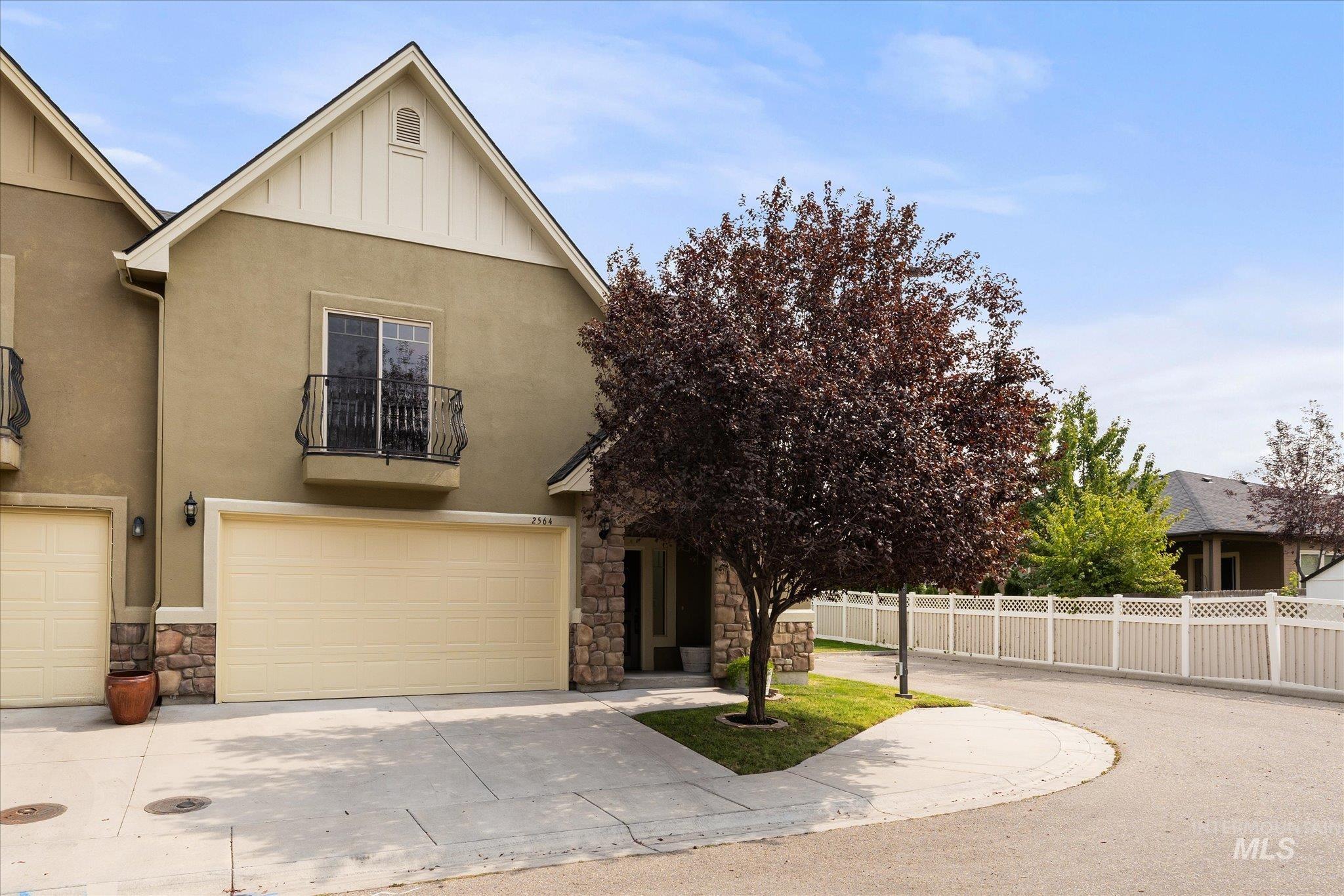 View of front of home featuring stone siding, driveway, a balcony, an attached garage, and board and batten siding