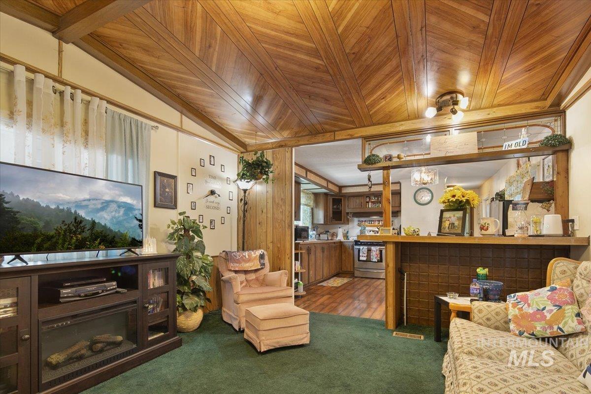 Living area featuring carpet flooring, wood ceiling, and vaulted ceiling
