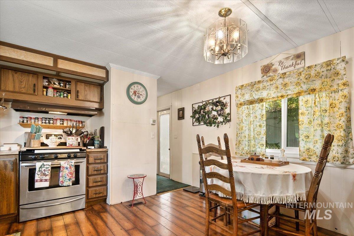 Dining space with dark wood-type flooring, a chandelier, and ornamental molding