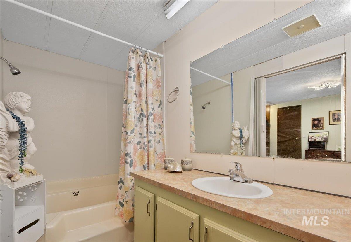 Bathroom featuring shower / bath combination with curtain and vanity