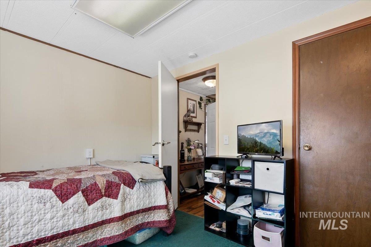 Bedroom with wood finished floors and ornamental molding
