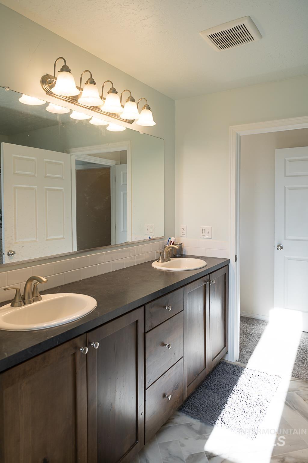 Full bath featuring double vanity and backsplash