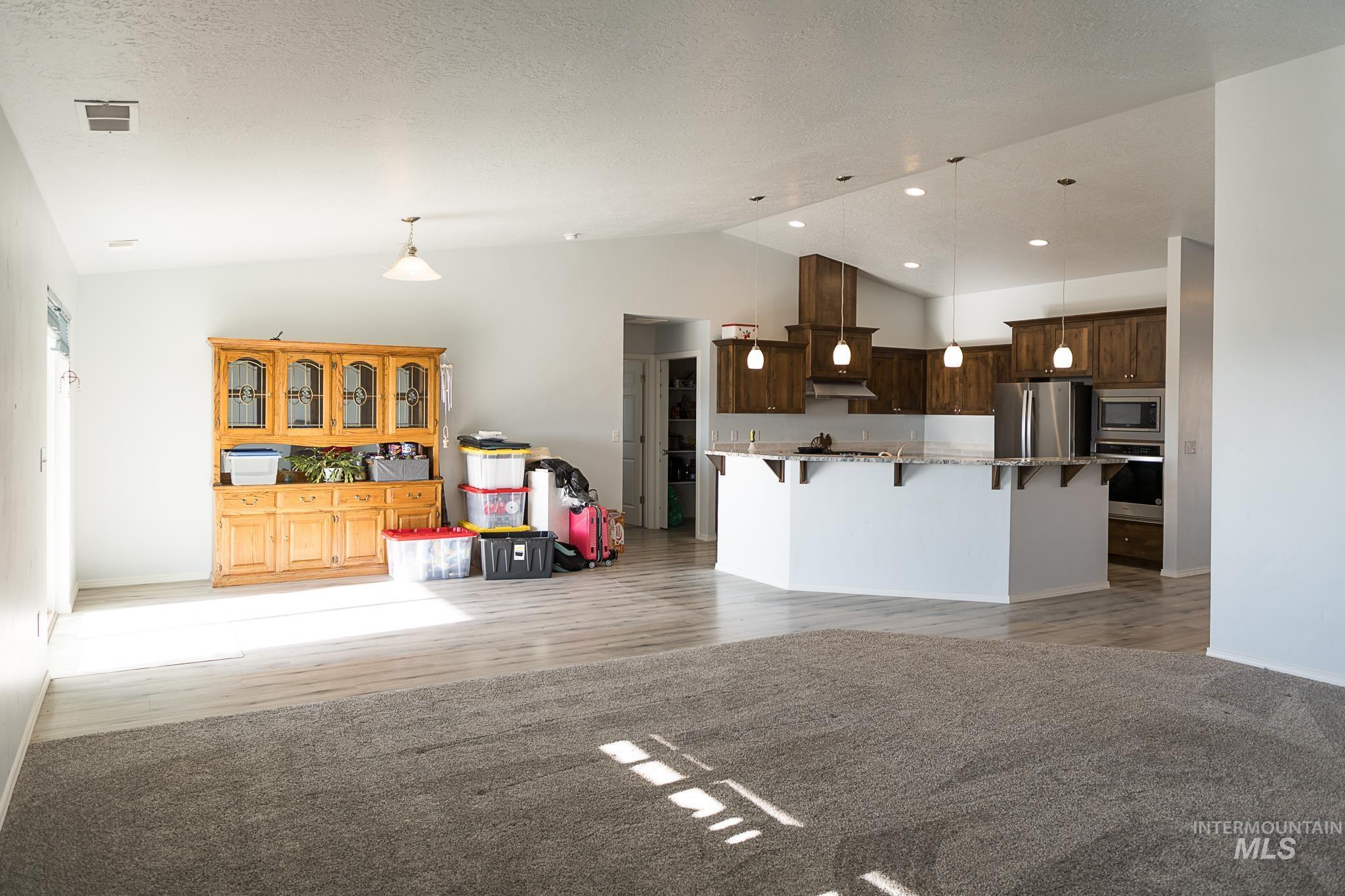 Kitchen featuring a breakfast bar area, decorative light fixtures, open floor plan, vaulted ceiling, and stainless steel appliances