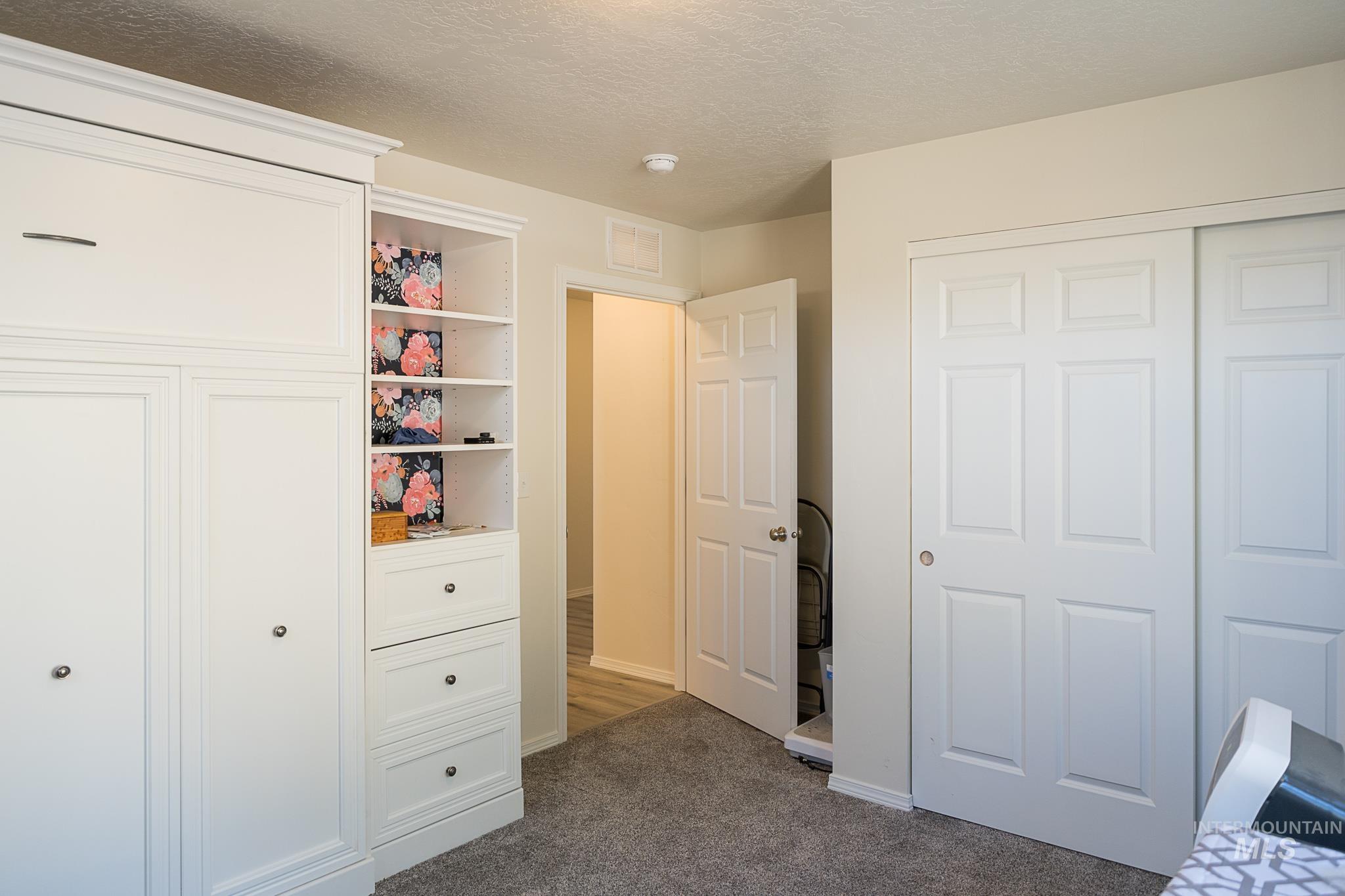 Bedroom featuring a closet, a textured ceiling, and dark carpet