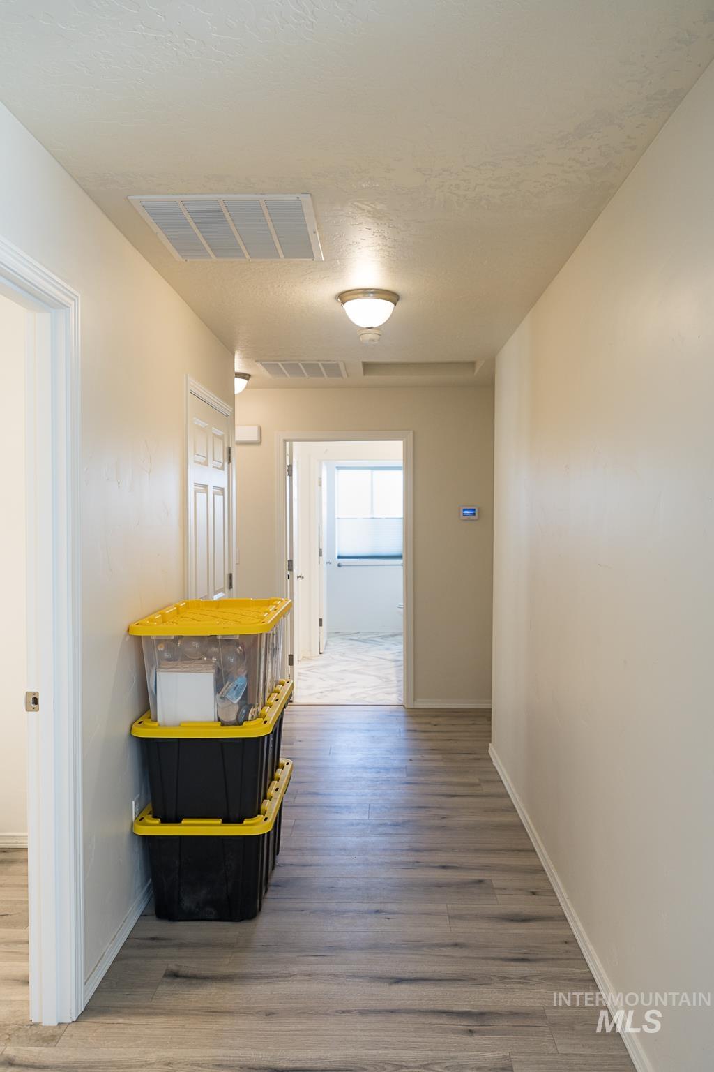 Hall with light wood-style flooring and a textured ceiling