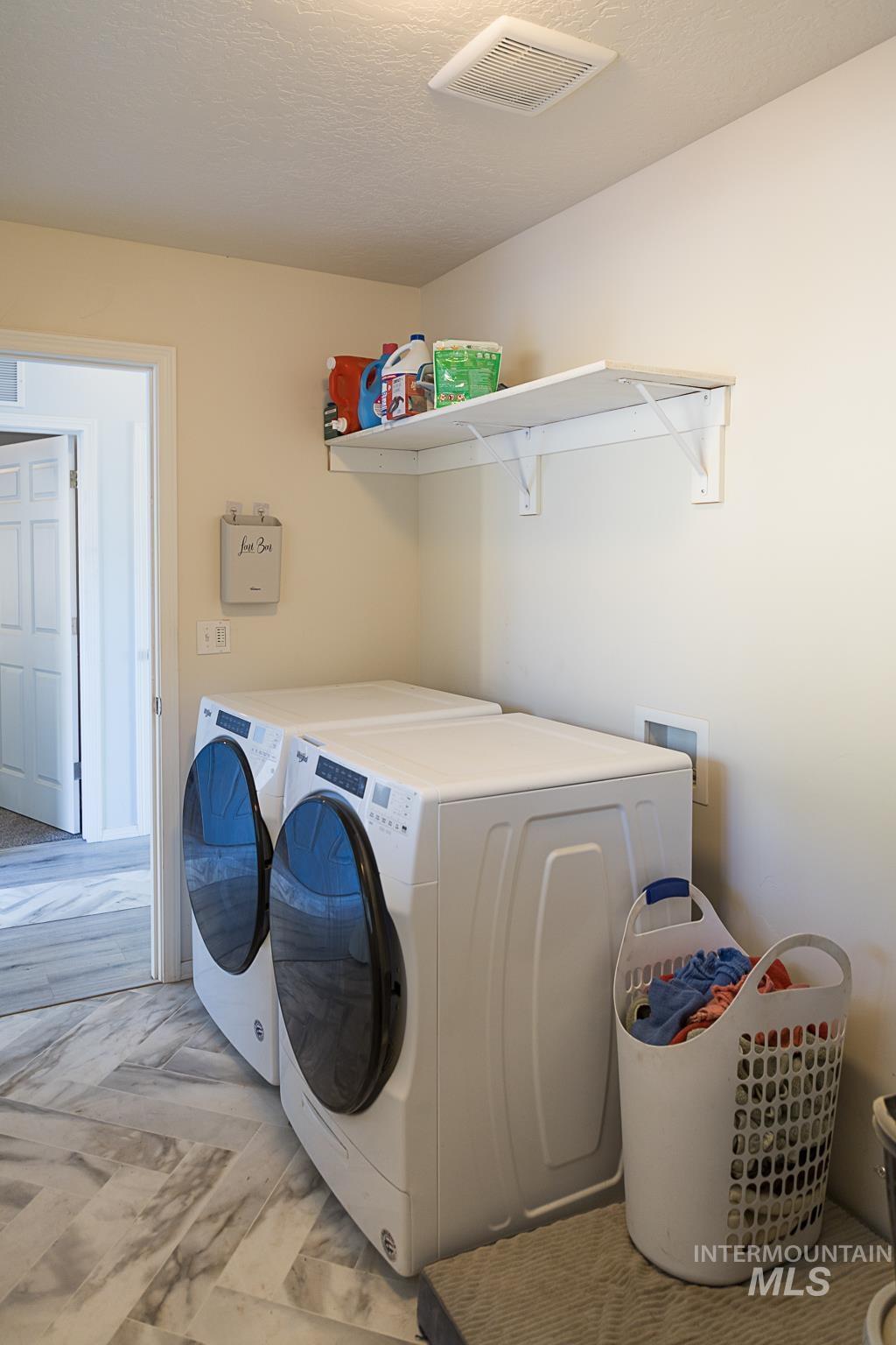 Washroom with washing machine and clothes dryer and a textured ceiling