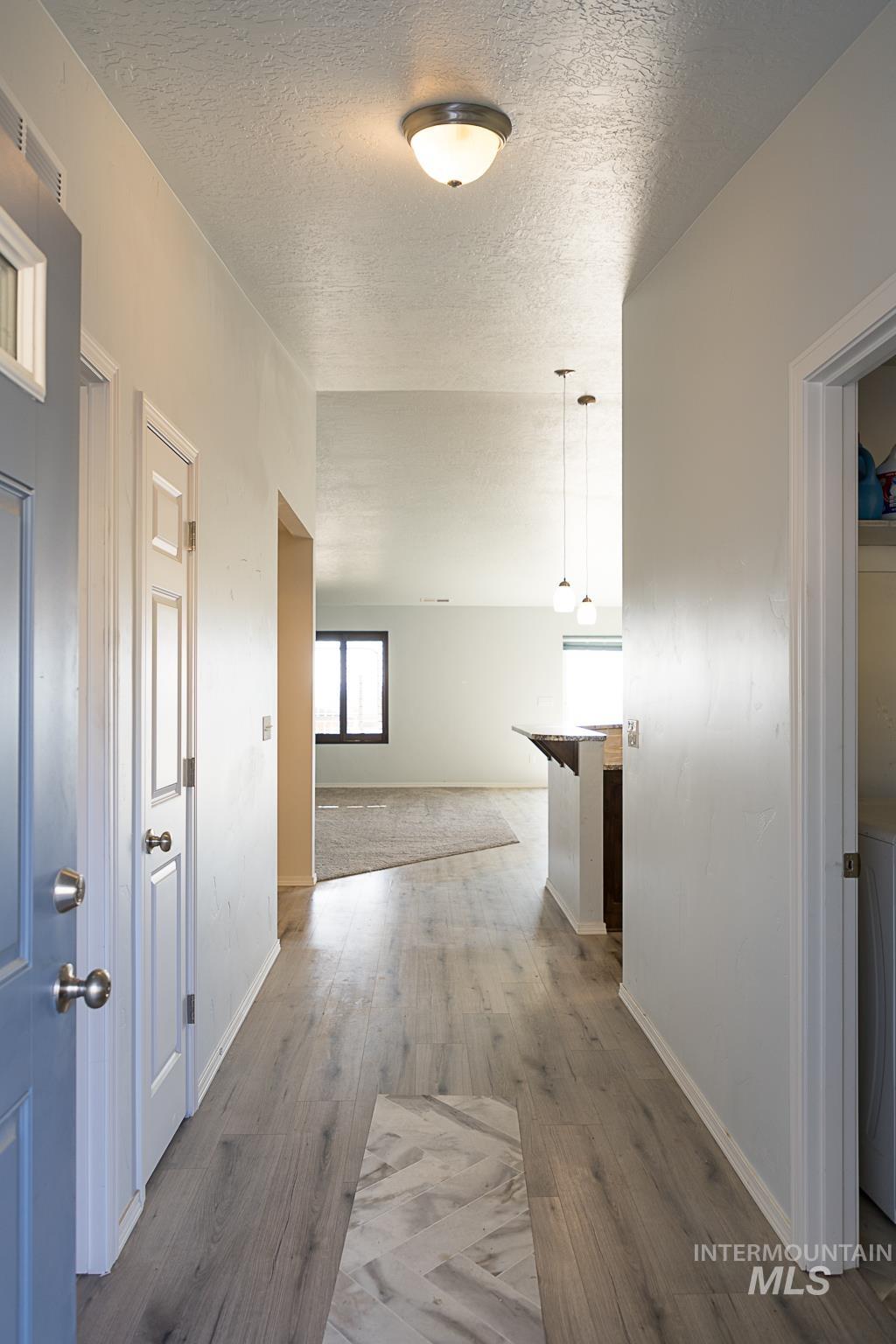 Corridor with a textured ceiling and wood finished floors