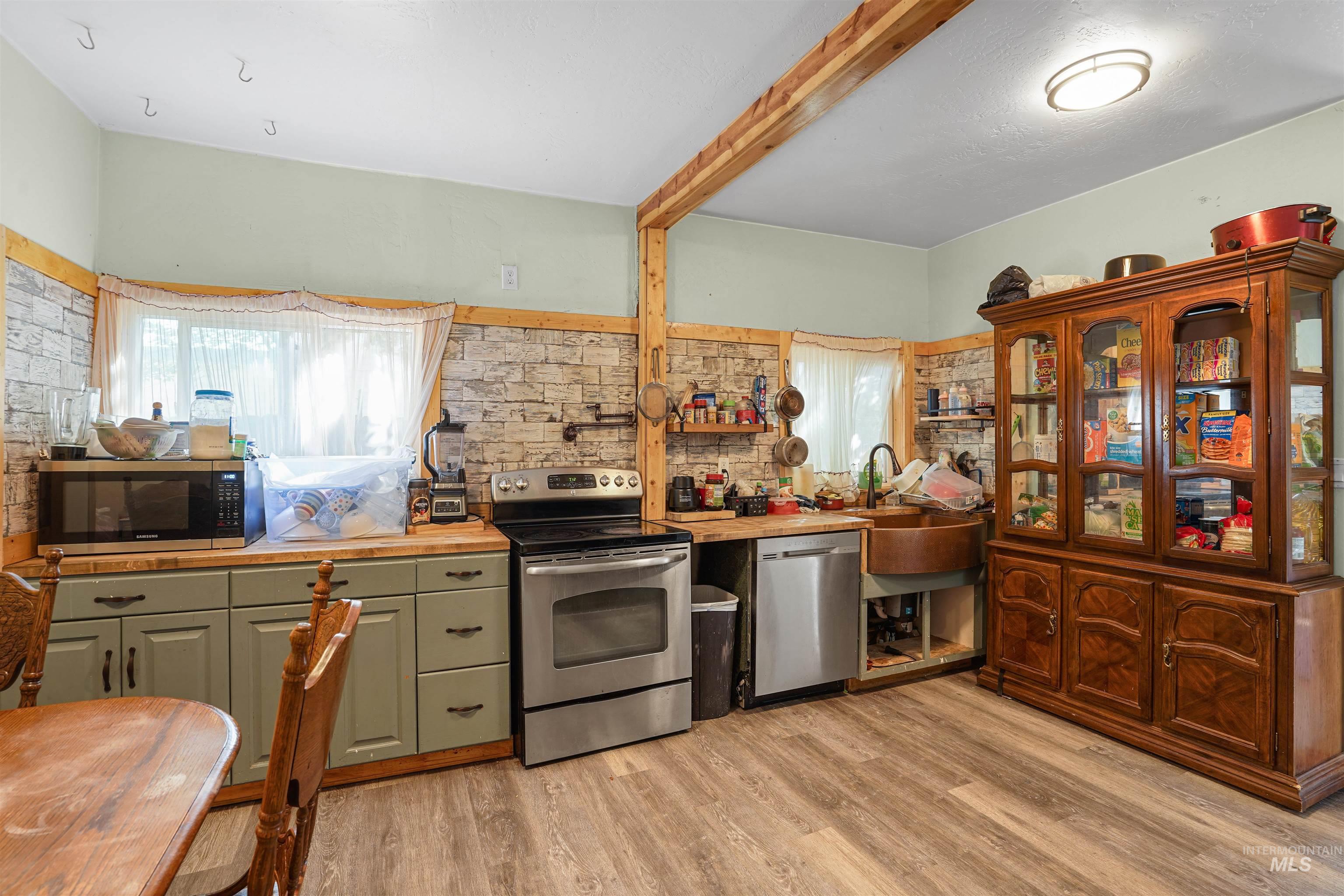 Kitchen featuring appliances with stainless steel finishes, light wood-type flooring, wood counters, and decorative backsplash