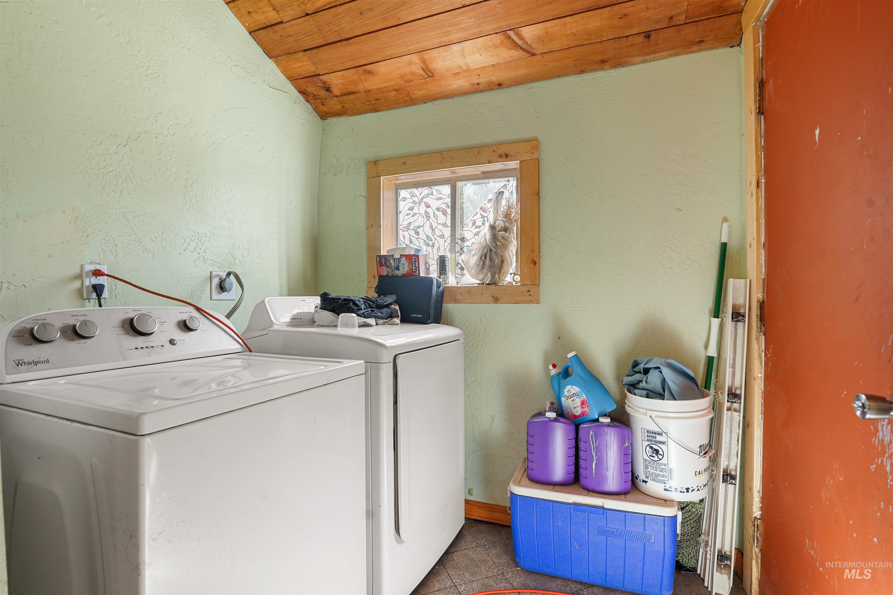 Laundry room with a textured wall, wood ceiling, separate washer and dryer, and tile patterned floors