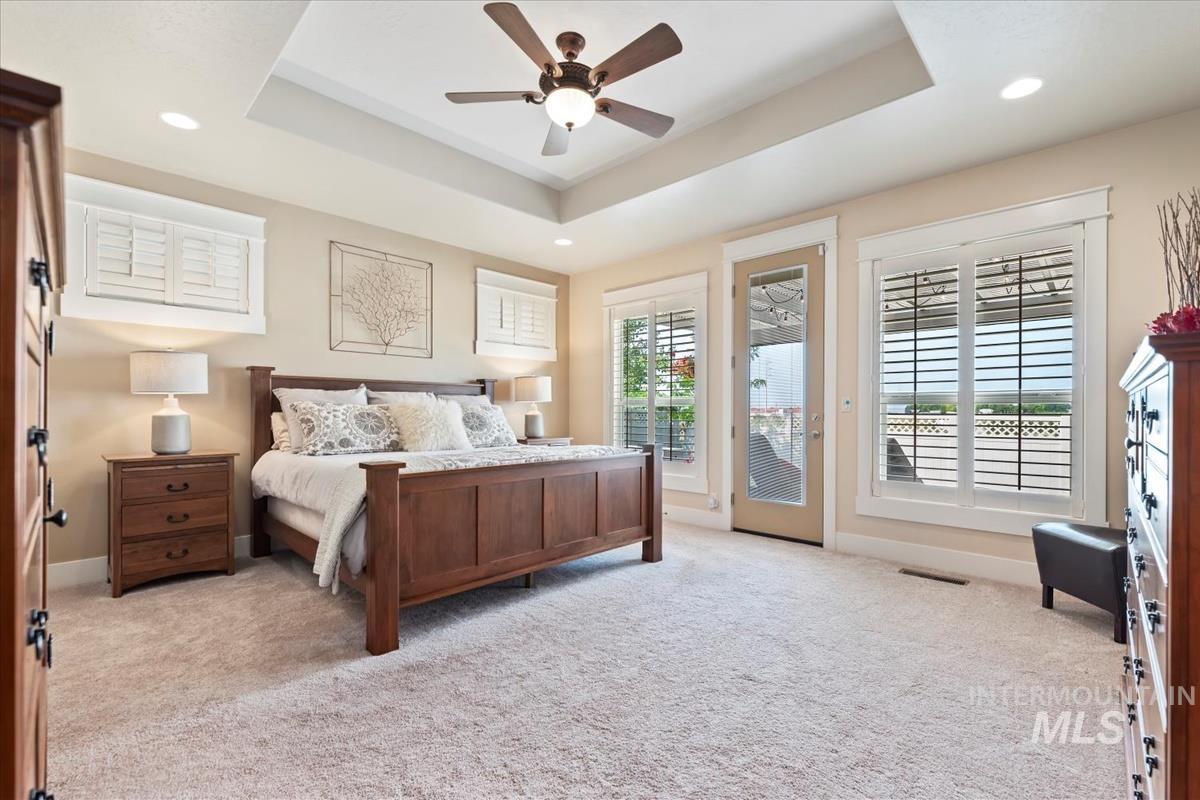 Bedroom with a raised ceiling, light carpet, access to outside, and recessed lighting