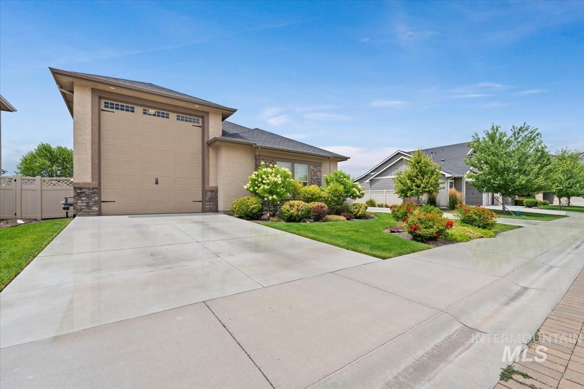 Prairie-style home with driveway, stone siding, an attached garage, and stucco siding
