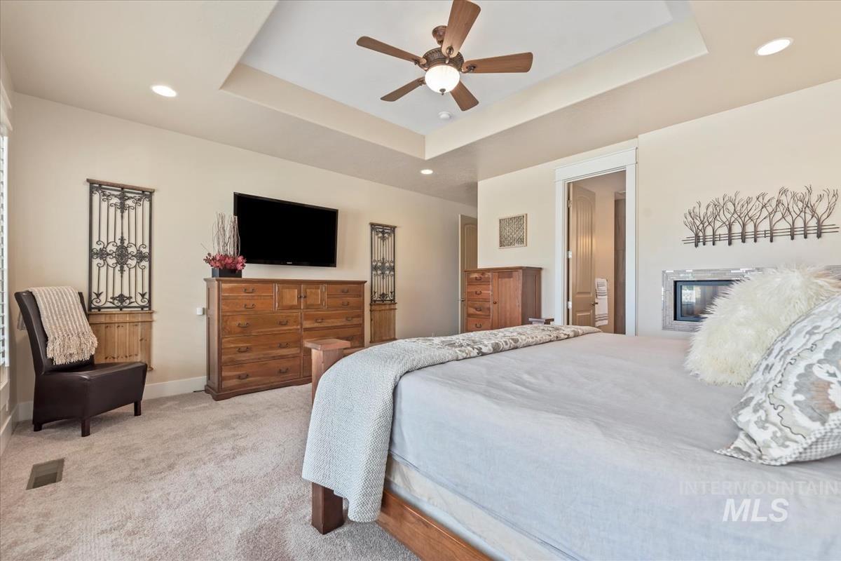 Carpeted bedroom with a tray ceiling, recessed lighting, and ceiling fan