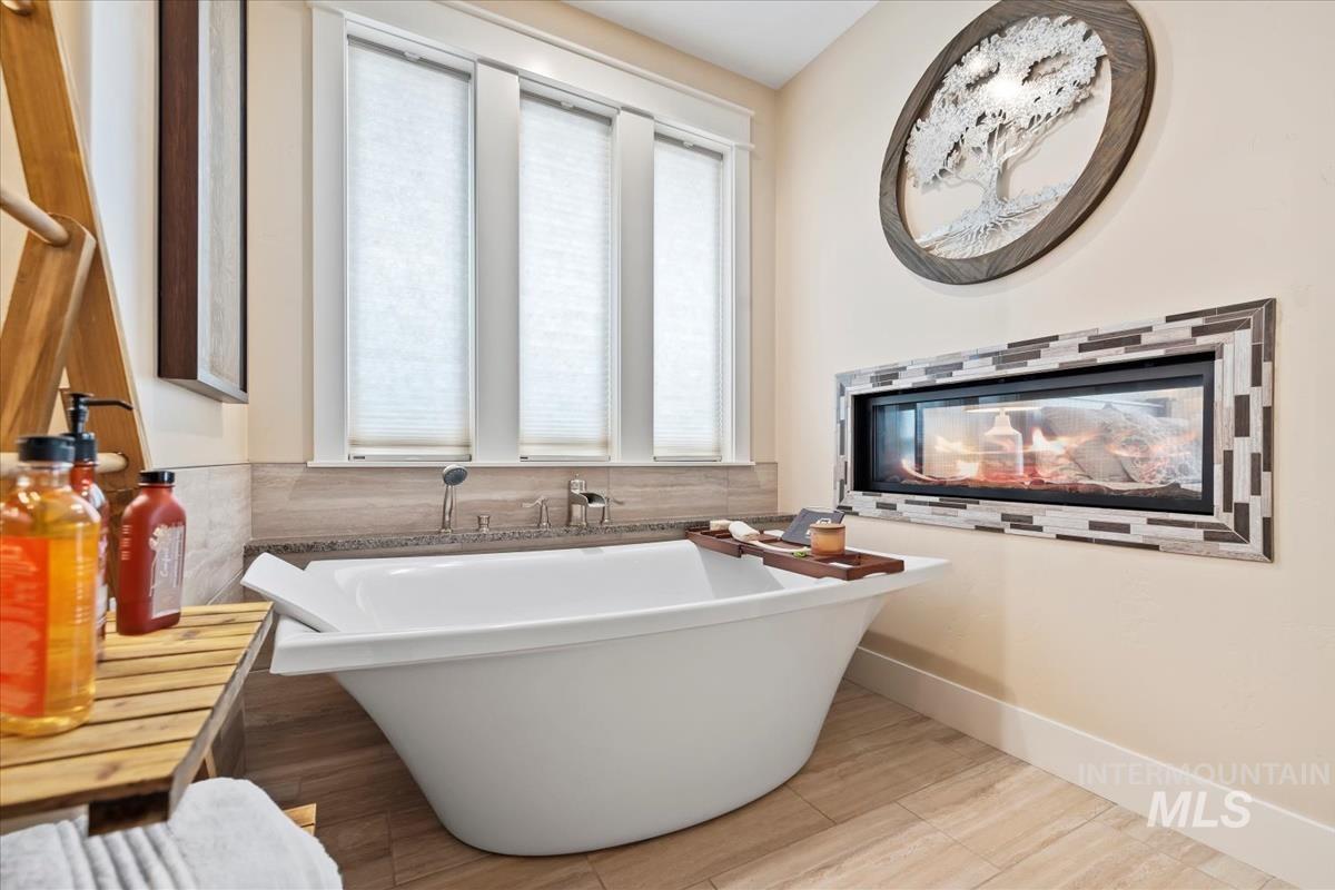 Full bath with a soaking tub and baseboards