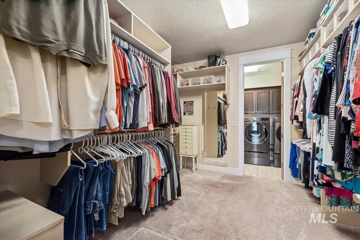 Spacious closet featuring light carpet and washer and dryer