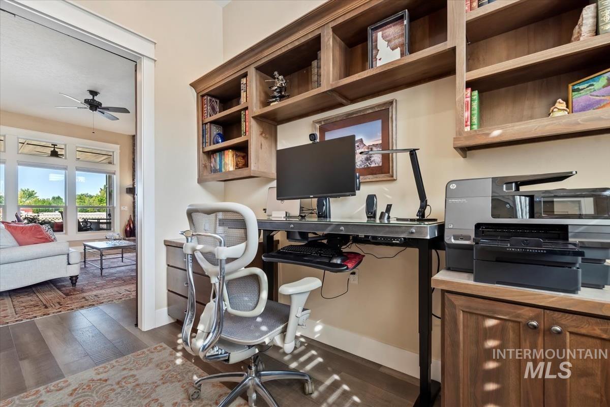 Home office with a ceiling fan and dark wood-style floors