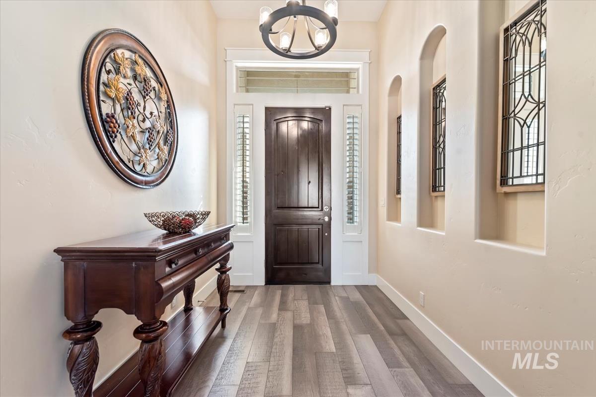 Foyer entrance with wood finished floors and a chandelier