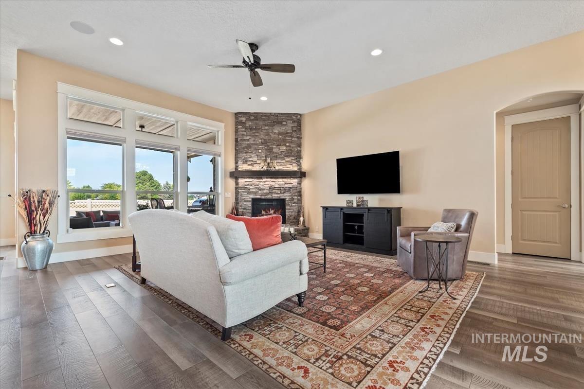Living room with recessed lighting, wood finished floors, a fireplace, a ceiling fan, and arched walkways
