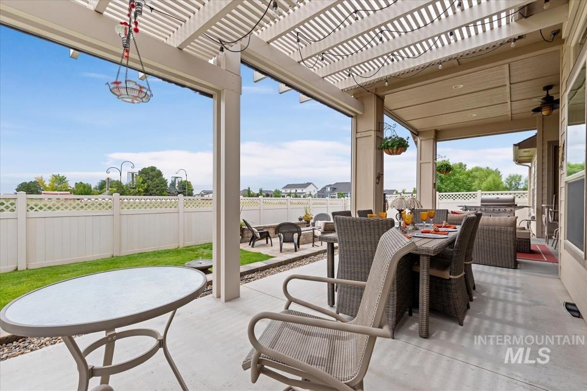 Fenced backyard with a patio area, outdoor dining space, a pergola, and a ceiling fan