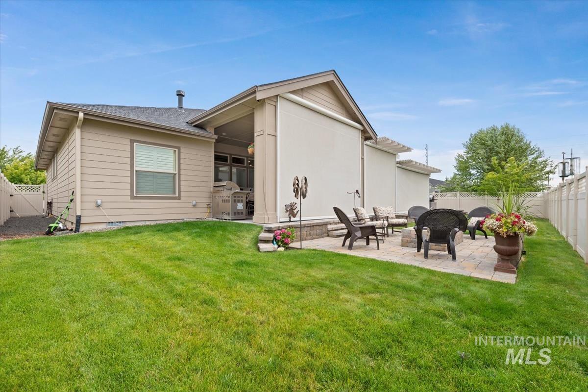 Rear view of house with a patio area, a fenced backyard, and roof with shingles