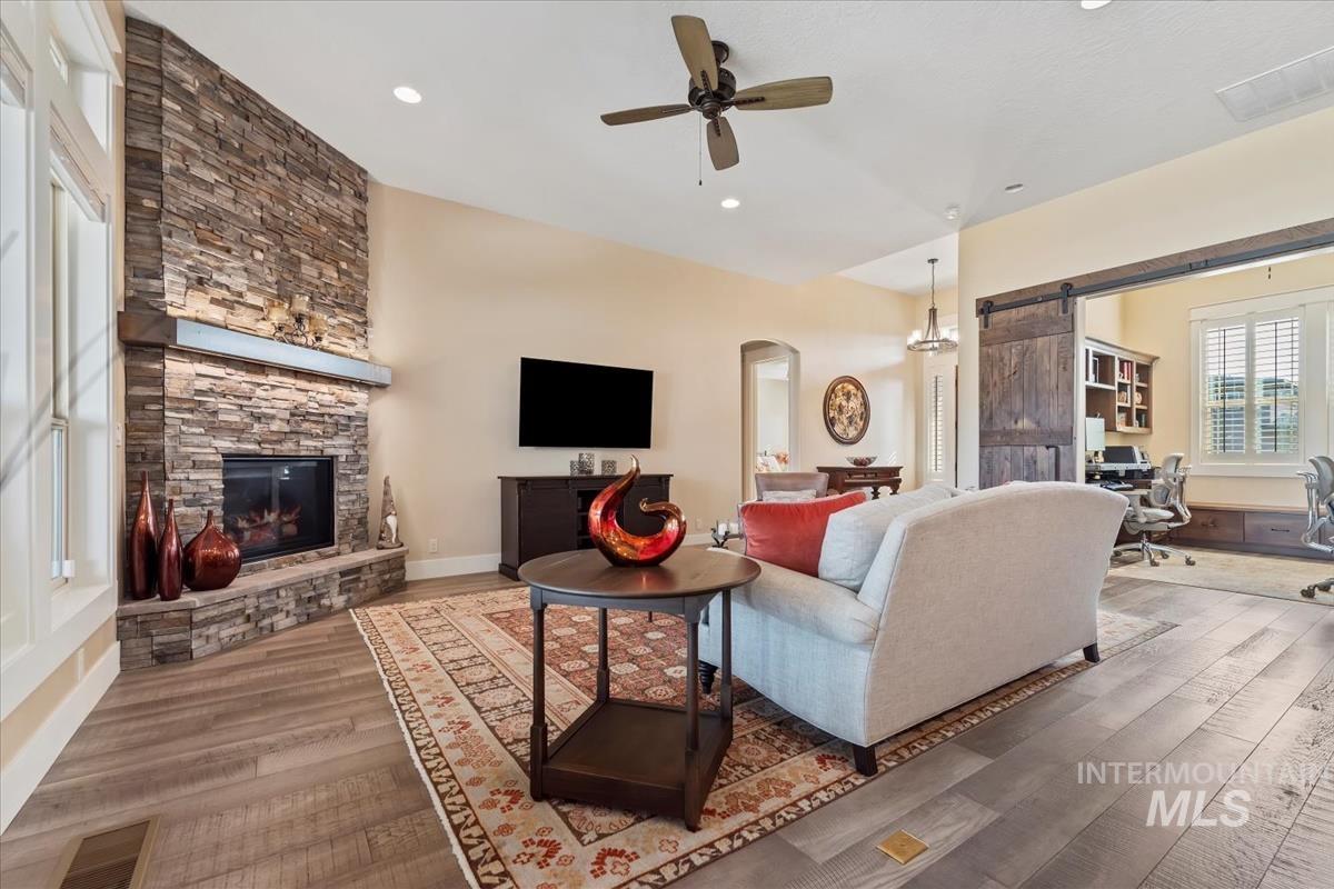 Living area with a barn door, a desk, wood finished floors, recessed lighting, and a ceiling fan