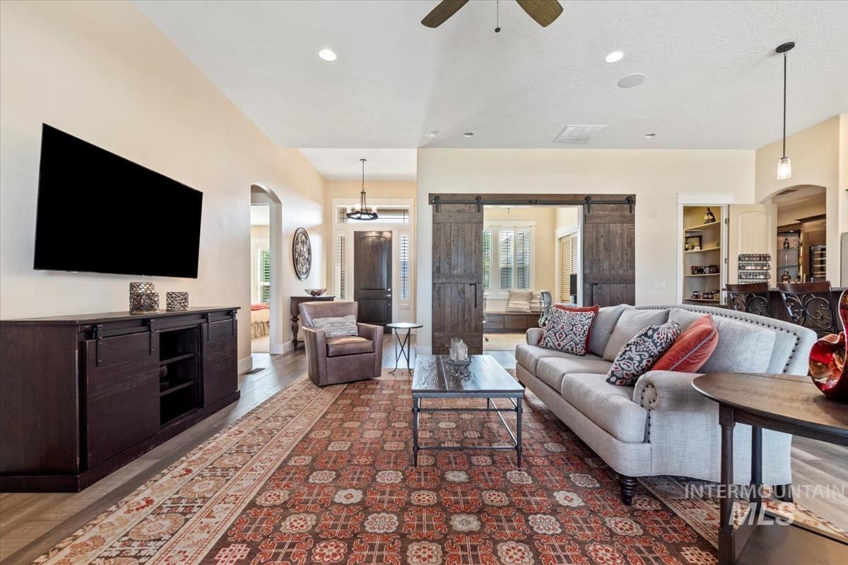 Living area with arched walkways, a barn door, wood finished floors, ceiling fan, and recessed lighting