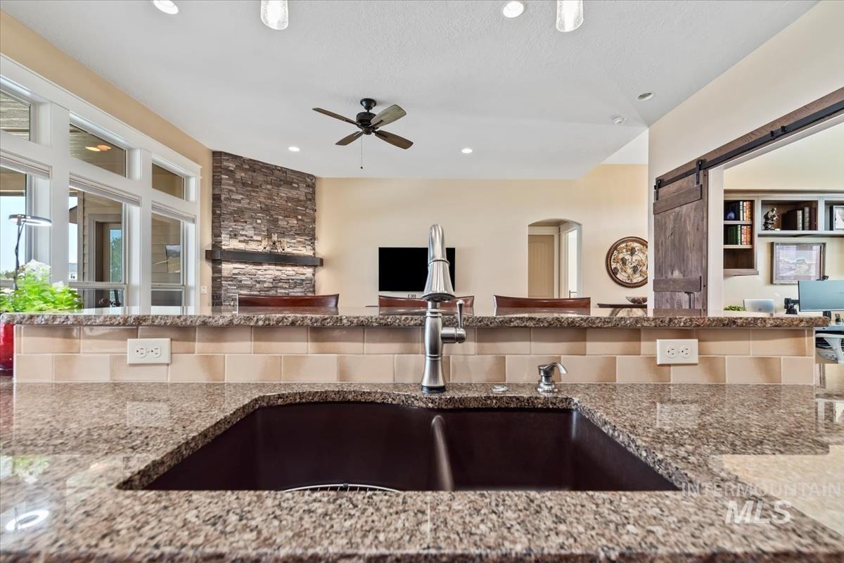 Kitchen featuring light stone counters, open floor plan, recessed lighting, a barn door, and a ceiling fan