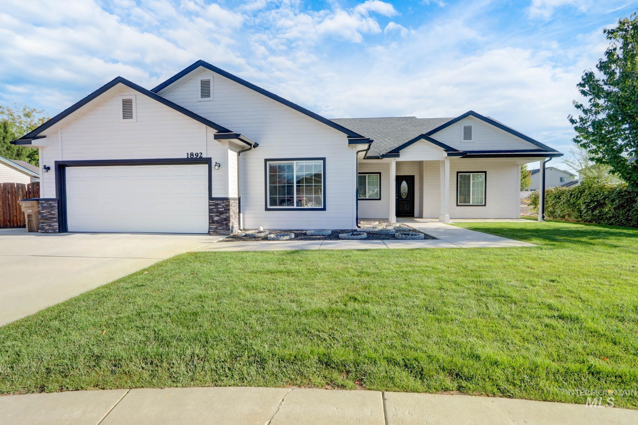 Modern inspired farmhouse featuring concrete driveway, an attached garage, covered porch, and stone siding