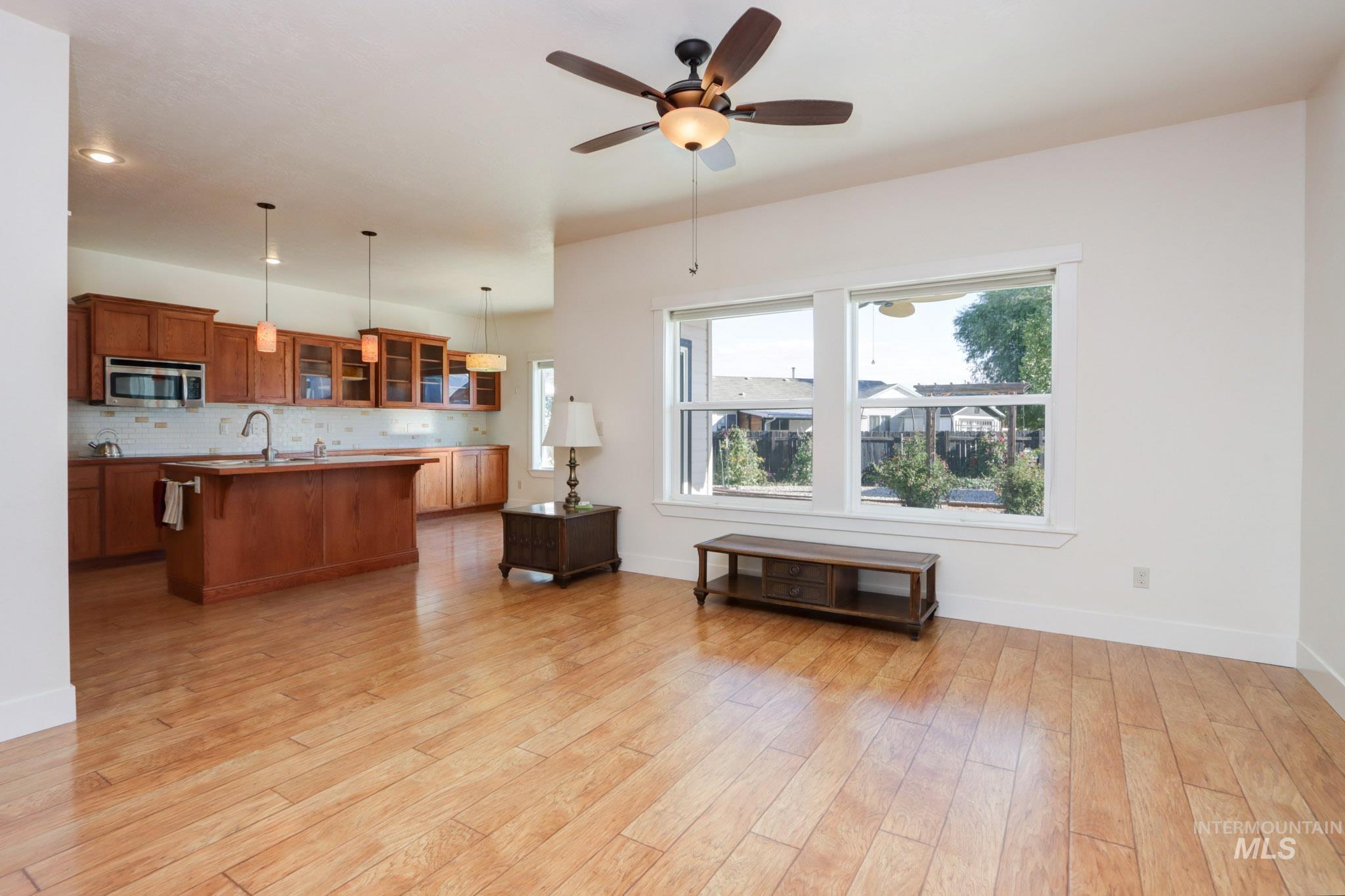 Living room with ceiling fan, light wood finished floors, and recessed lighting