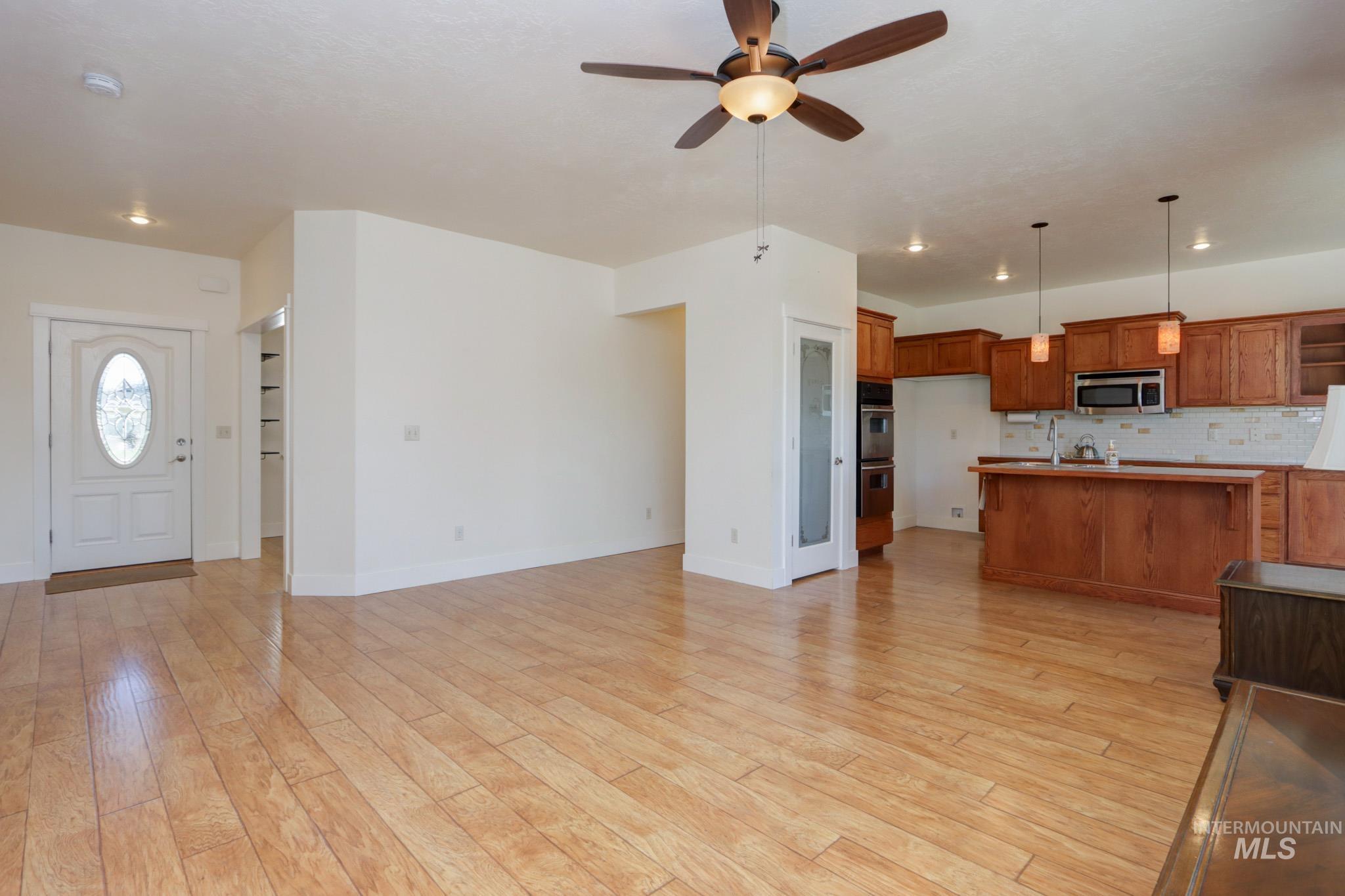 Kitchen featuring brown cabinetry, decorative backsplash, hanging light fixtures, open floor plan, and recessed lighting