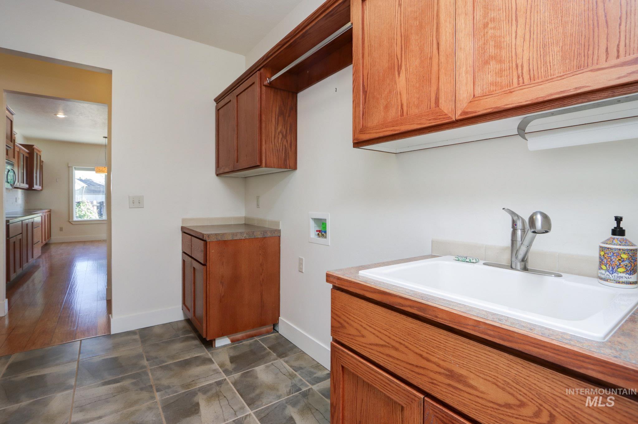 Laundry area featuring washer hookup, cabinet space, and dark tile patterned flooring