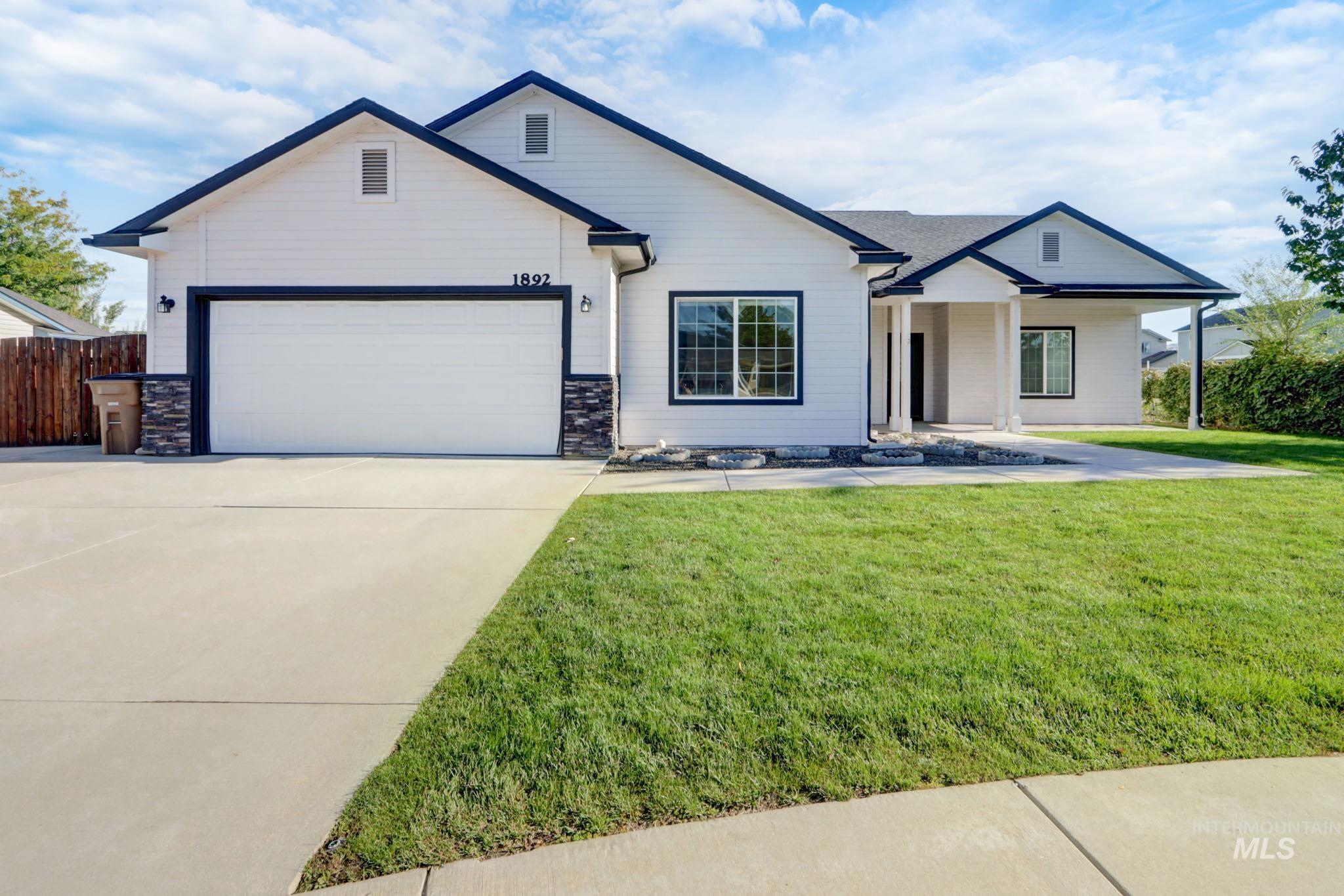 View of front of house with stone siding, concrete driveway, an attached garage, and covered porch