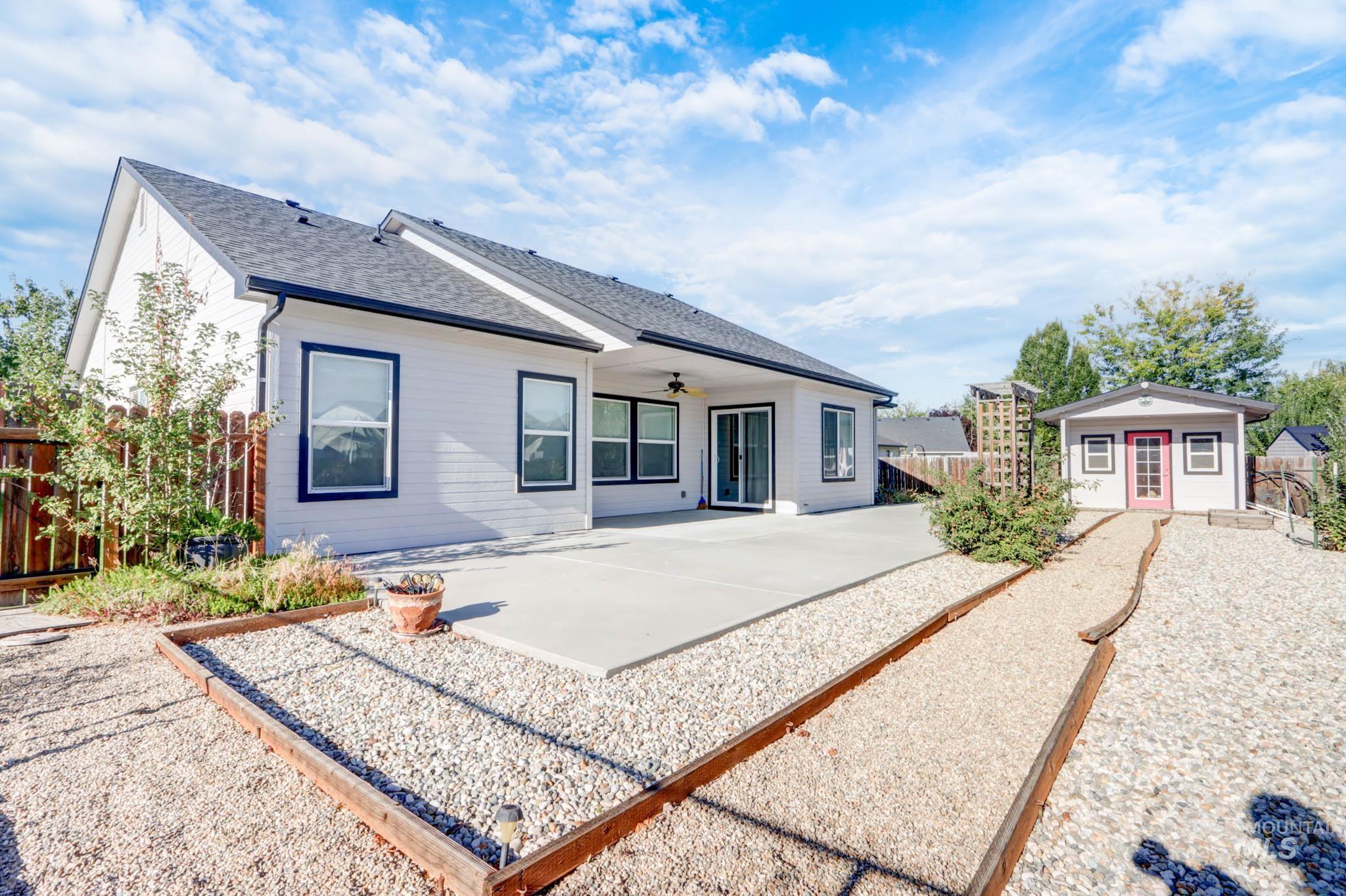 Rear view of property featuring a fenced backyard, a patio area, an outbuilding, a shingled roof, and a ceiling fan