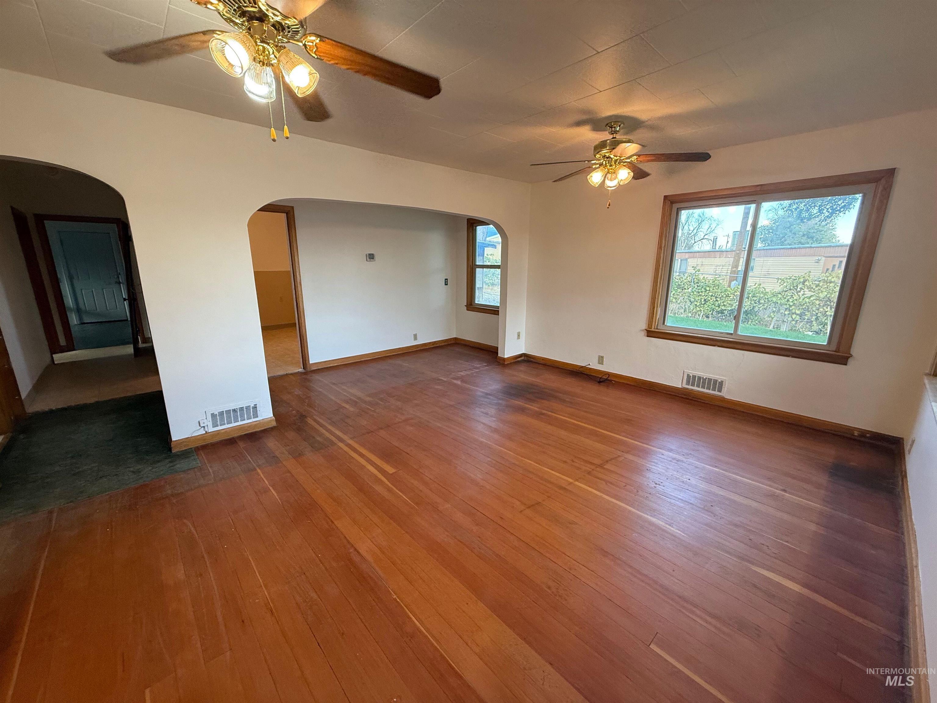 Spare room with a ceiling fan, hardwood / wood-style flooring, plenty of natural light, and arched walkways