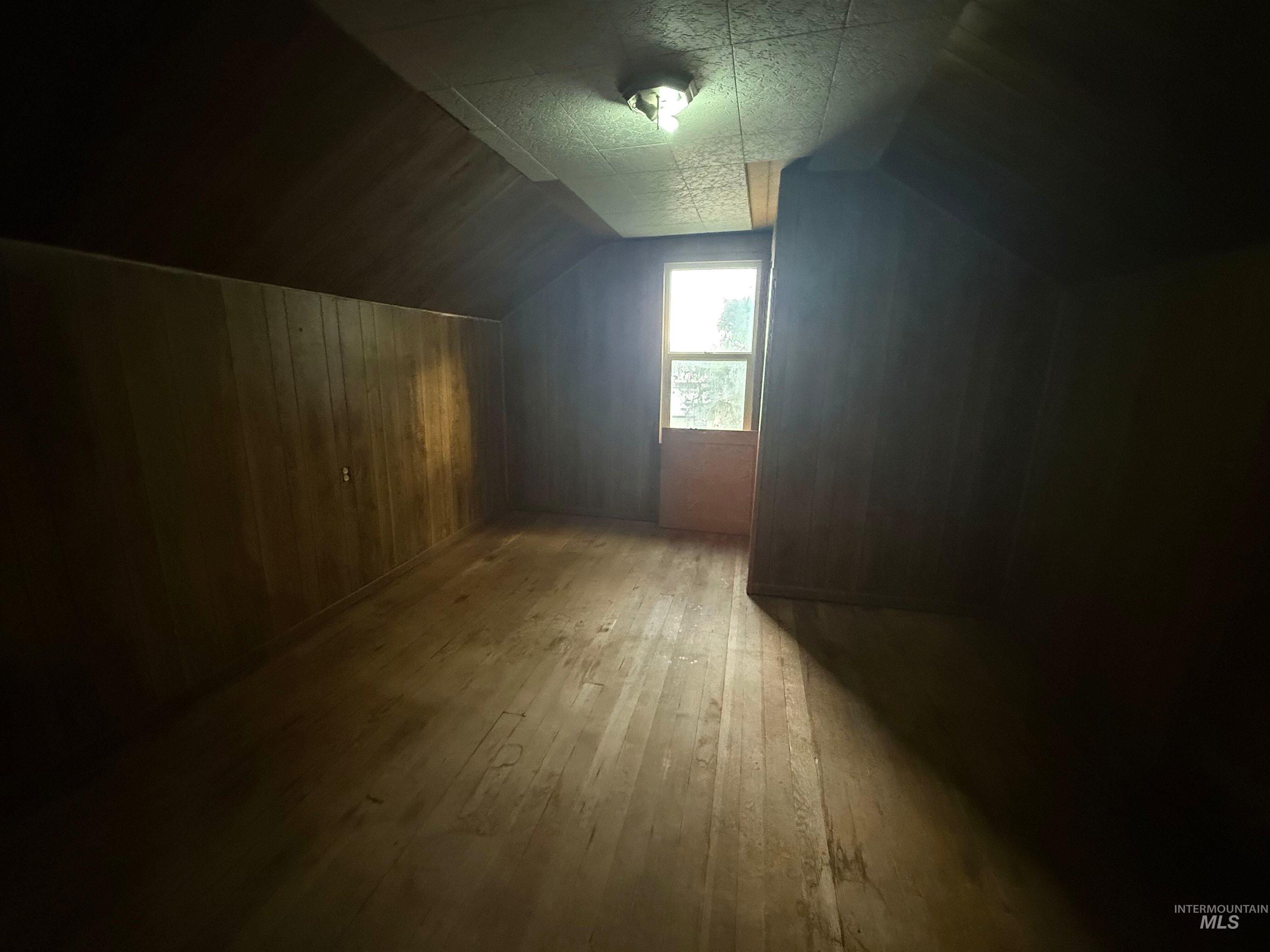 Additional living space with vaulted ceiling, hardwood / wood-style floors, and a textured ceiling