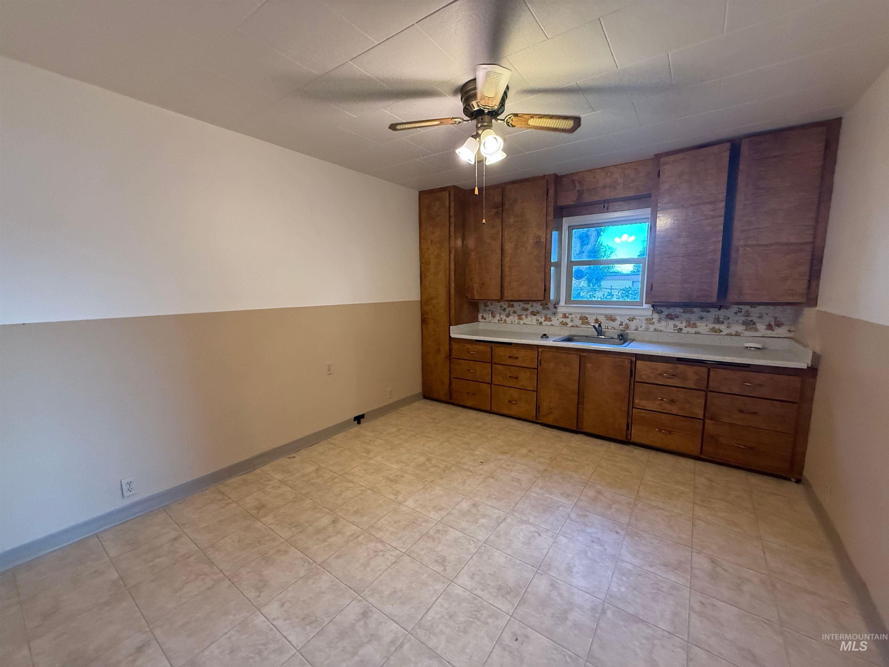 Kitchen with light countertops, brown cabinetry, tasteful backsplash, and ceiling fan