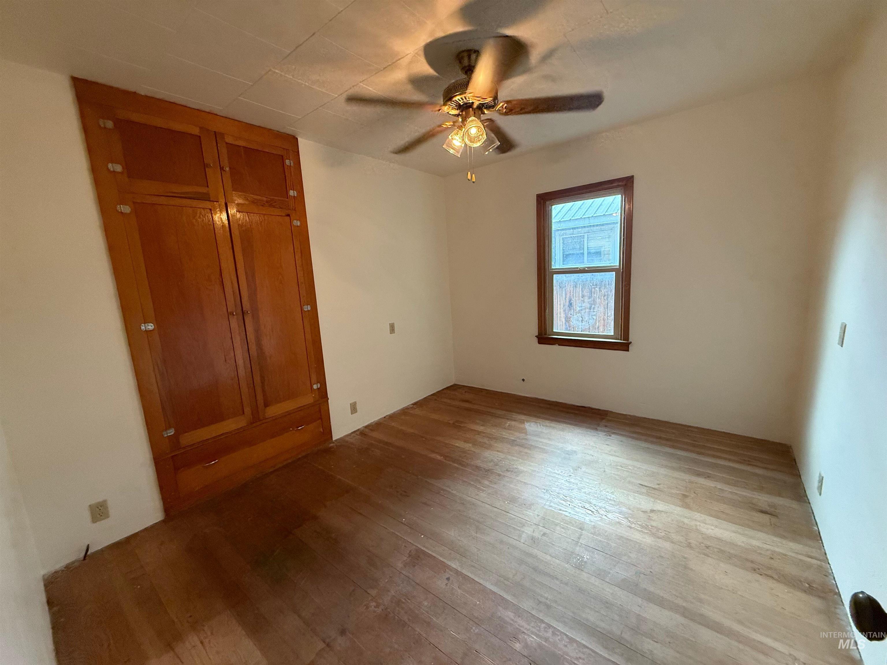 Unfurnished bedroom with wood-type flooring, a closet, and ceiling fan