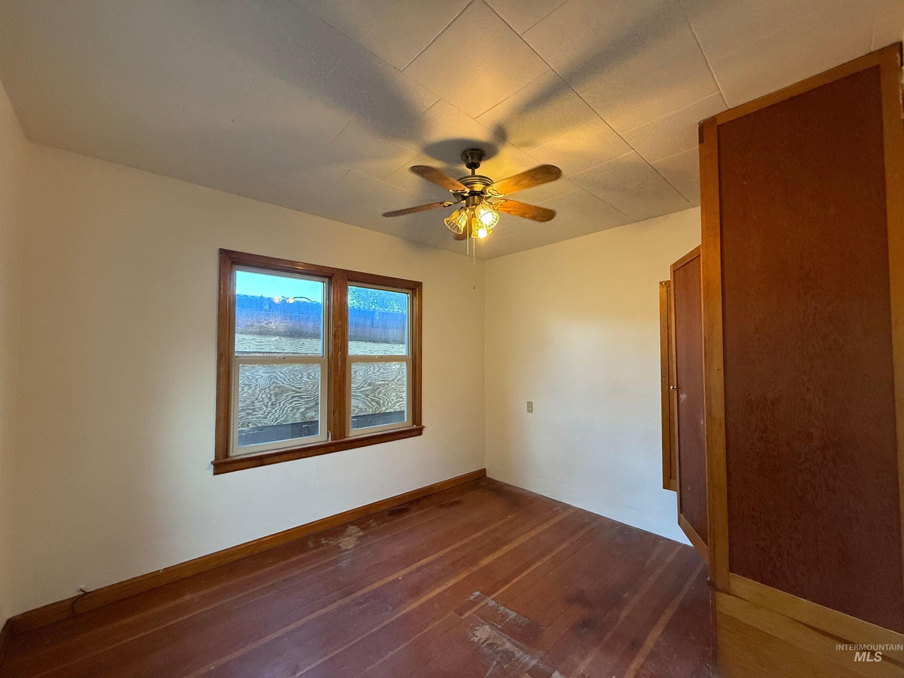 Unfurnished room with dark wood-type flooring and a ceiling fan