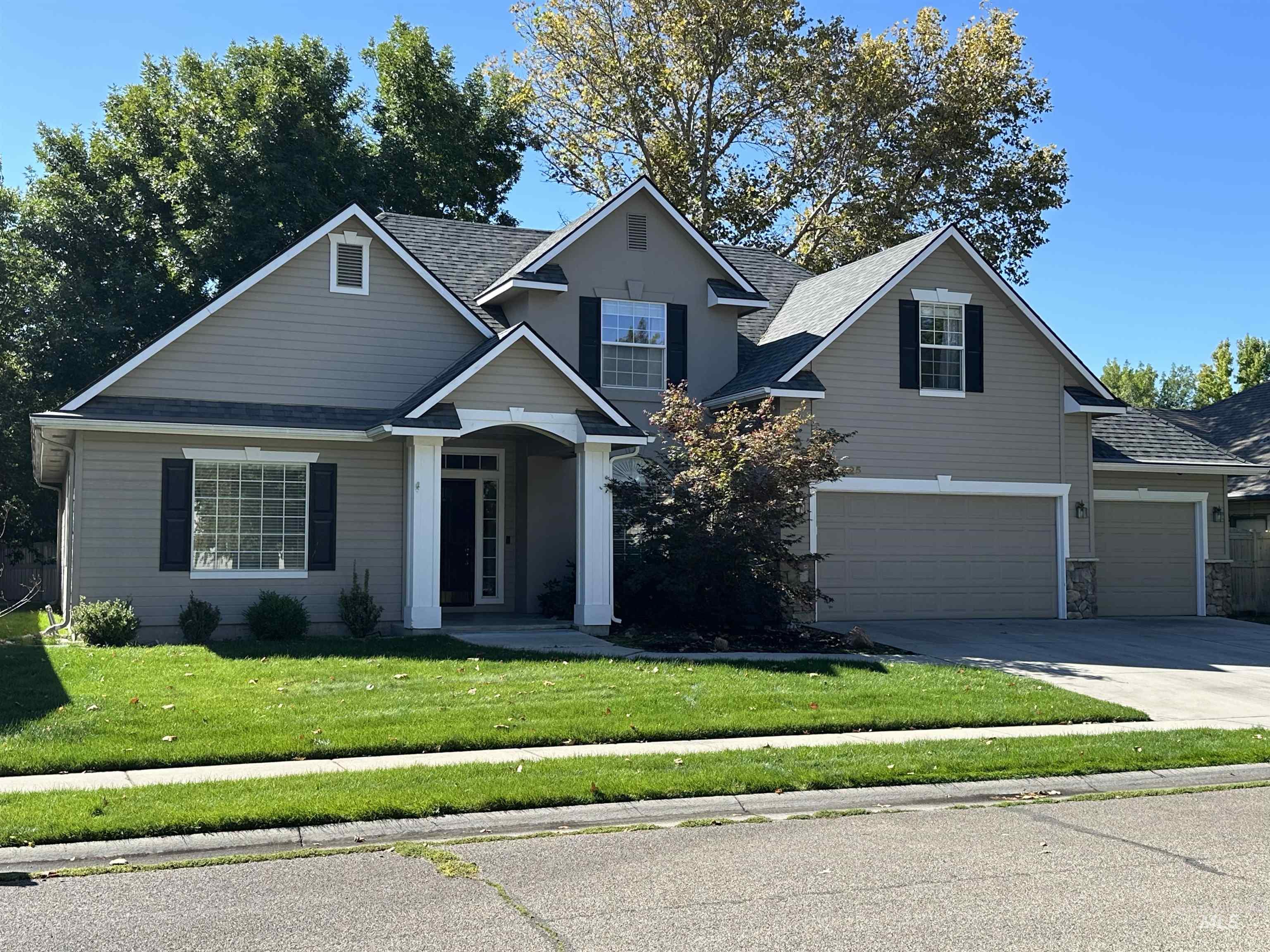 Traditional home featuring driveway, a front lawn, and roof with shingles