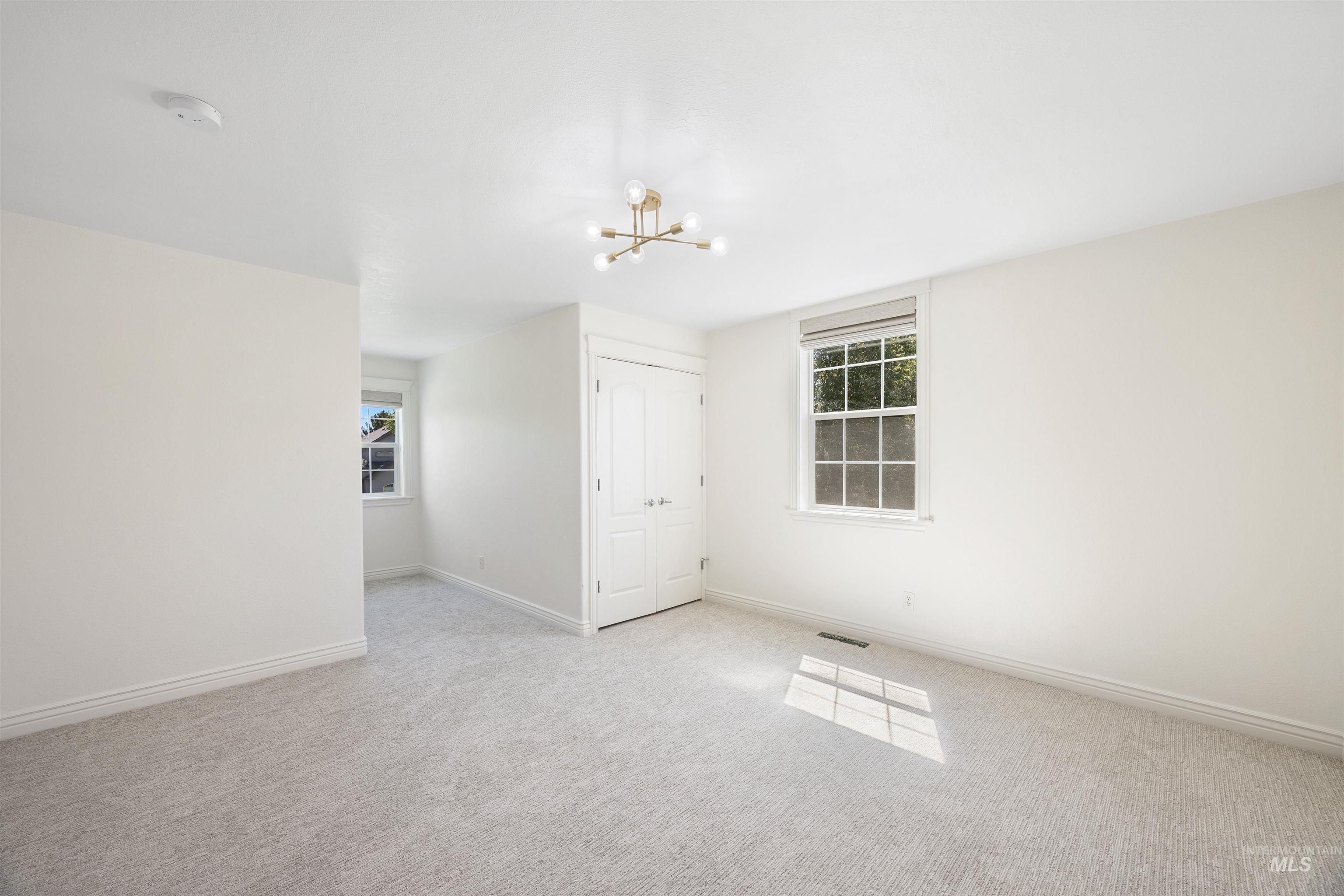 Carpeted spare room with baseboards and a chandelier