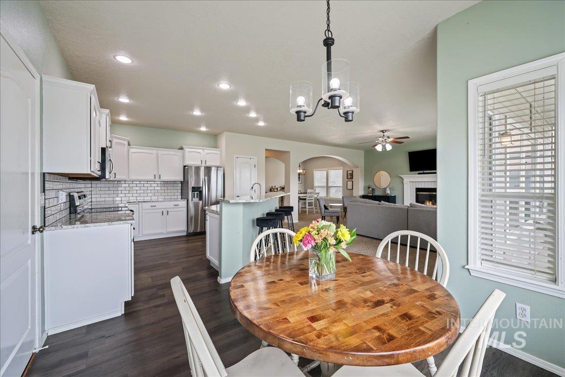 Dining room with arched walkways, a chandelier, dark wood finished floors, a ceiling fan, and recessed lighting