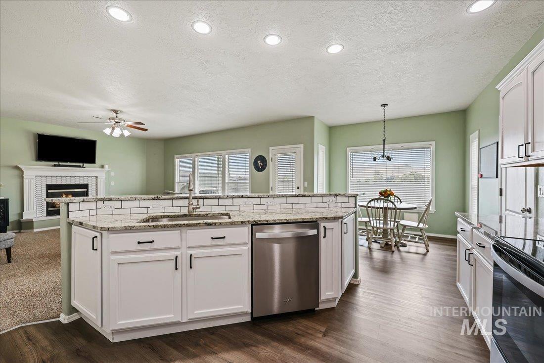 Kitchen featuring white cabinets, stainless steel appliances, light stone countertops, a textured ceiling, and recessed lighting