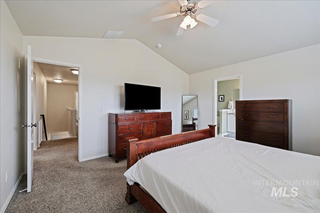 Carpeted bedroom featuring lofted ceiling, a ceiling fan, and ensuite bathroom