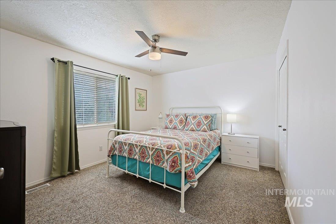 Bedroom featuring carpet floors, a textured ceiling, and a ceiling fan