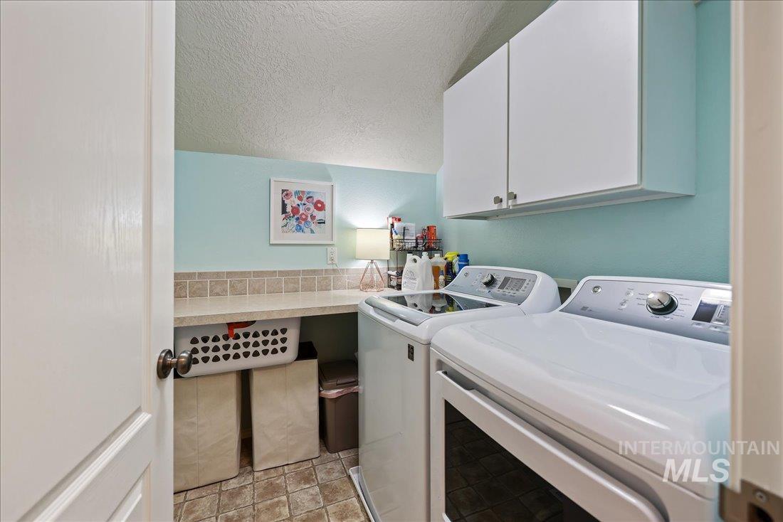 Laundry area with a textured ceiling, cabinet space, and washer and clothes dryer